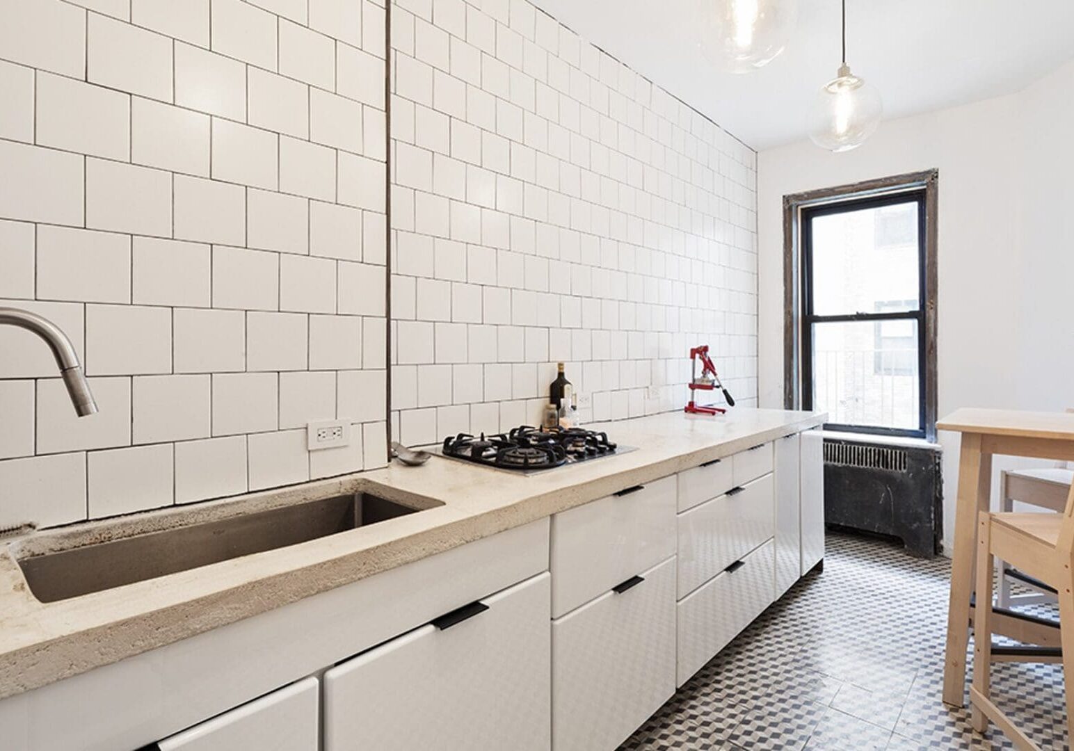 A kitchen with white cabinets and tiled walls.